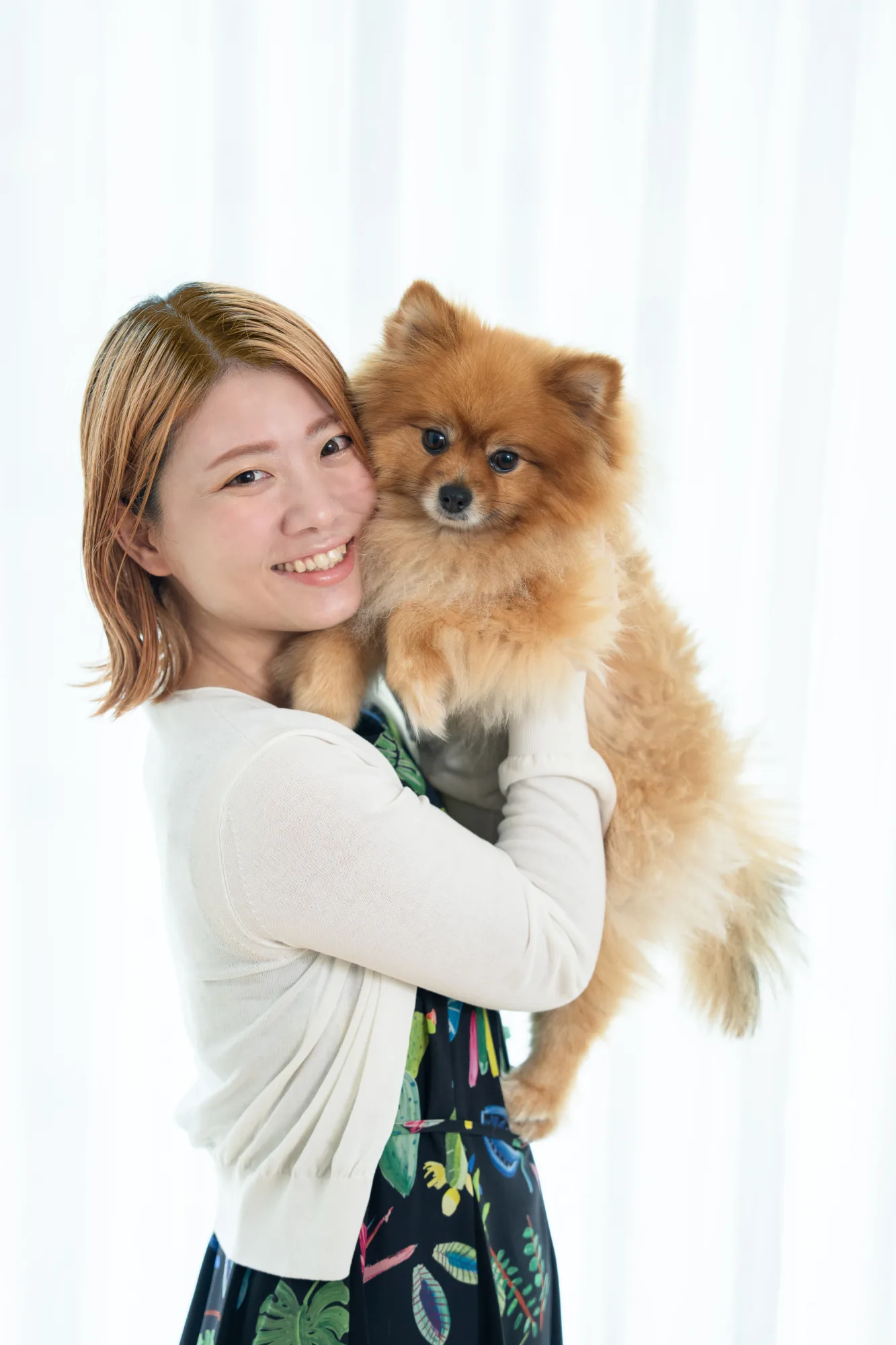 ポメラニアンを抱いて微笑む女性のポートレート
