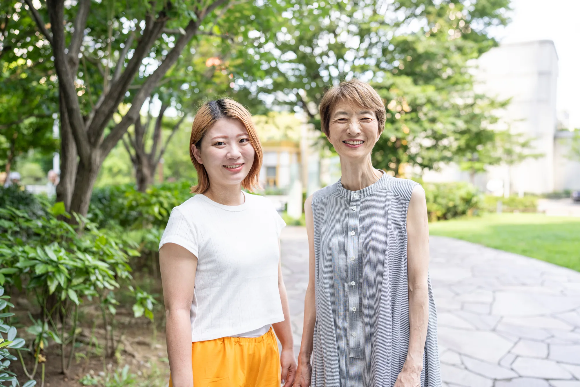 緑の公園の小道に並んで立つ母娘